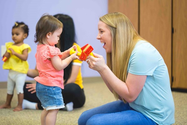 A mom and her toddler playing with a Kindermusik Red/Yellow Jingle Bell