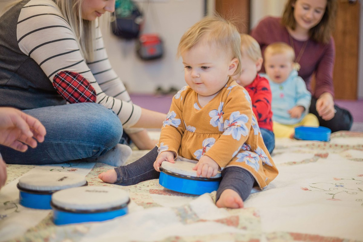 Baby exploring handheld drum. What to expect in a music class for babies and infants.