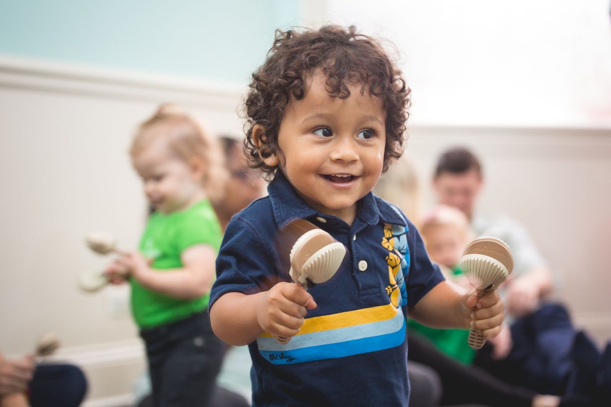 Toddler playing castanets. What to expect in a music class for toddlers.