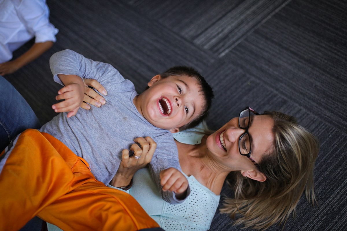 A mom and her son laughing and enjoying a mixed-ages Kindermusik class.