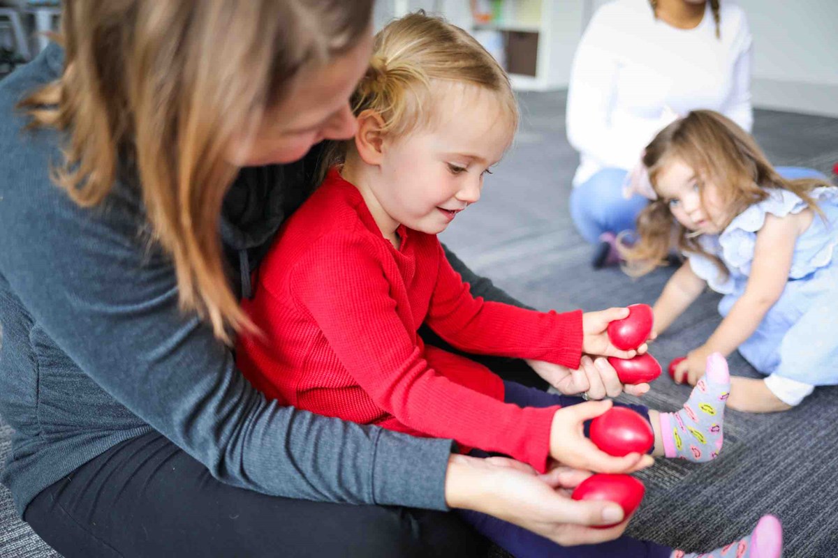 Parents and their two-year-olds playing with egg shakers in a Level 2 Kindermusik class.