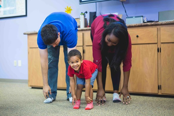 A preschooler and his parents touching their toes in a Level 3 Kindermusik class