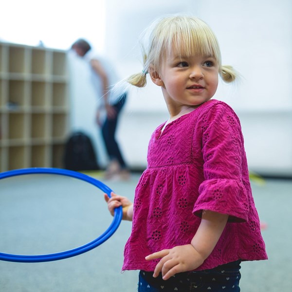 Two-year-old girl plays with a hoop during music classes for older toddlers
