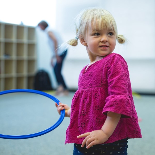 Two-year-old girl plays with a hoop during music classes for young toddlers